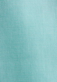 Gros plan sur un tissu bleu clair avec un motif répétitif de petites formes géométriques bleu sarcelle formant une grille texturée.