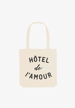 Borsa a tote in tela, colore crema, con la scritta "HÔTEL de l'amour" in caratteri neri in grassetto. Manici per un facile trasporto.