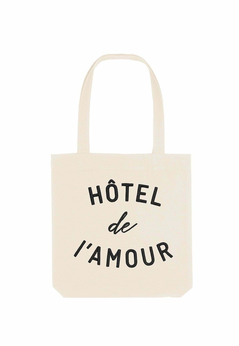 Borsa a tote in tela, colore crema, con la scritta "HÔTEL de l'amour" in caratteri neri in grassetto. Manici per un facile trasporto.