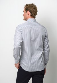 Gestreepte shirt in wit en marineblauw, met een button-down kraag, lange mouwen met knoopmanchetten, een gebogen zoom en een gemêleerd stofpatroon.