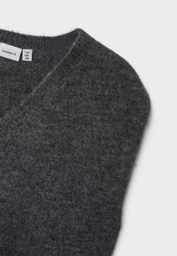 Grå genser i ullblanding med V-hals, myk tekstur og en litt løs passform. Merkeetiketten er synlig på sømmen i kragen.