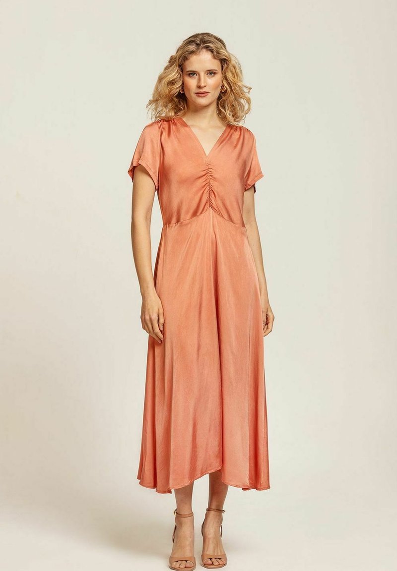 Midikjol i mjuk persikofärgad tyg; har korta ärmar, en V-ringning och rynkdetaljer fram, med en flödande A-linjeformad siluett.
