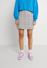 Checkered mini skirt with blue, pink, and cream patterns, paired with a light blue sweater and pink sneakers with white accents.