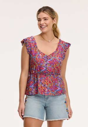 Bunte Blumenbluse mit V-Ausschnitt, gerafften kurzen Ärmeln und einem gerafften Bund. Kombiniert mit hellen Jeansshorts mit bestickten Akzenten.