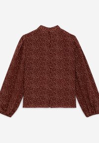 Blouse rouge foncé à manches longues avec petit motif abstrait à pois blancs, col montant et poignets boutonnés, vue de dos.