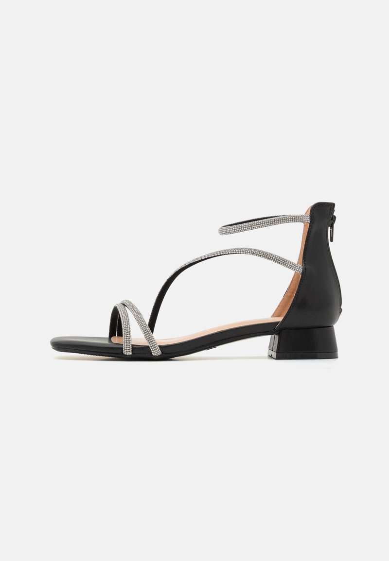 Sandales noires avec un petit talon carré, dotées de bandes métalliques ornées de strass. Semelle lisse et design minimaliste.