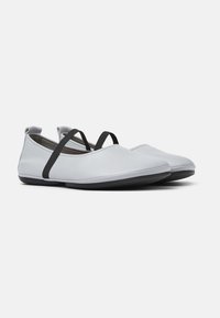Scarpe in pelle grigia chiara con suola piatta, dotate di cinghie elastiches nere sulla parte superiore per una vestibilità sicura e un design minimalista.