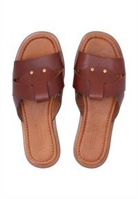 Bruine leren slip-on sandalen met een kruisspeld ontwerp, voorzien van gouden studs en een comfortabele tan inlegzool. Glad textuur en ronde vorm.