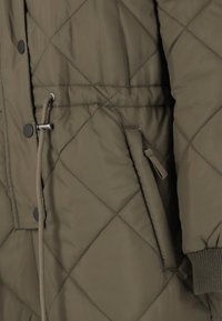 Oliivinvihreä tikattu puffer-takki, jossa on kapea vyötärö, napit ja vetoketjullinen tasku, varustettuna ribbitetyillä hihoilla ja sileällä pinnalla.