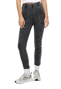 Szare dżinsowe legginsy z elastycznym pasem, dopasowanym krojem oraz detalami przeszycia z boku, w połączeniu z szaro-białymi trampkami.