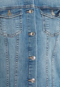 Jeansjacka i ljusblå färg, med två bröstfickor, silverknappar och kontrasterande sömmar längs sömmarna och knapplist.