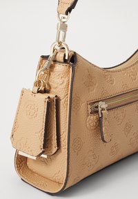 Borsa a tracolla in pelle beige strutturata con accessori in oro, dotata di una tasca con zip e di un'etichetta staccabile, che presenta un motivo a logo impresso.