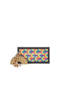 Metalowy breloczek w kolorze złotym, w kształcie tęczy, z dekoracyjnymi okrągłymi ćwiekami. Dołączony kolorowy pudełko z nadrukiem w okrągłe wzory.