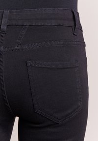 Jeans in denim scuro con un design aderente, caratterizzati da uno stile a cinque tasche e cuciture tonali sulla tasca posteriore.