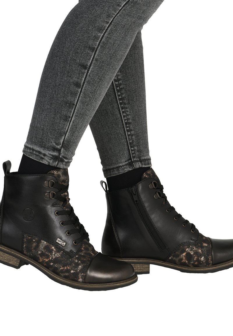 Beneden in grijze strakke spijkerbroek, zwart leren veterlaarsjes met luipaardprint stof en ritssluiting aan de zijkant.