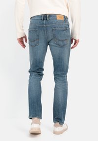 Blauwe spijkerbroek met een slim fit, met achterzakken, een lichte wassing en een bruine leren logopatch. Gekocht met lichtgekleurde sneakers.