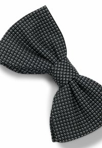 Schwarze Fliege aus strukturiertem Stoff mit einem geometrischen Muster aus kleinen weißen Quadraten und Rauten, in der Mitte verknotet.