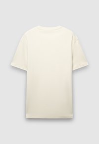 T-shirt a maniche corte, dalla vestibilità ampia, di colore crema, caratterizzata da un collo tondo e da un tessuto di cotone liscio e leggermente strutturato. Senza grafiche o design.