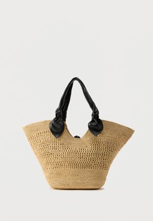 Austa šiaudinė rankinė plačiu, trikampio formos siluetu, juodomis odinėmis rankenomis su mazgais ir atvira viršutine dalimi. Natūralios šiaudų spalvos su tekstūra.