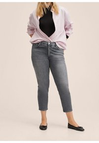 Jeans alla caviglia grigi abbinati a un top attillato nero e una camicia a righe rosa chiaro, con un taglio comodo e bottoni frontali. Ballerine nere.