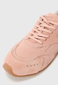 Baskets en suede rose avec un bout arrondi, des lacets plats, des détails de couture et une semelle en caoutchouc gomme. Présente des accents arrondis et des trous de ventilation minimaux.
