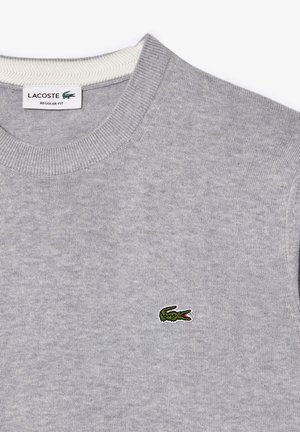 Felpa grigia con colletto a girocollo, polsini a coste e piccolo logo del coccodrillo Lacoste verde sul lato sinistro. Texture a maglia comoda.