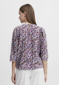 Floral blouse featuring purple, blue, and brown patterns on lightweight fabric. ¾ sleeves with a keyhole detail at the back.
