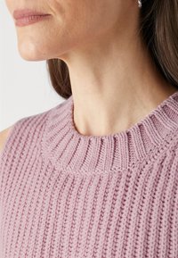 Pull en tricot côtelé de couleur rose doux, présentant un col haut et des détails fins. La texture est épaisse avec des rayures verticales.