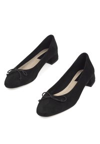 Bailarinas de ante negro con un bajo tacón cuadrado, punta redondeada y un lazo decorativo en la parte delantera. Textura suave y diseño simple.