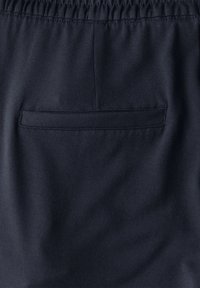 Marineblauwe stof, lichtgewicht en met een gladde textuur, heeft een elastische tailleband en een achterzak met een horizontale opening.