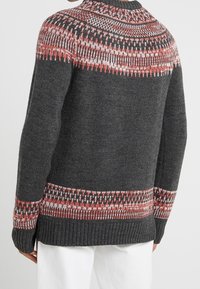 Pull en laine grise avec un yoke à motifs rouge et blanc, des poignets et un ourlet côtelés, un ajustement décontracté et des manches mi-longues.