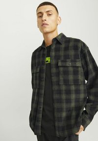 Langsleeve geruit overhemd in zwart en olijfgroen, met twee borstzakken en een knoopsluiting aan de voorkant. Gemaakt van een textiel met structuur.