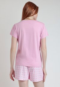 Camiseta de algodón rosa con mangas cortas y un corte relajado, combinada con pantalones cortos rosa a cuadros con un patrón sutil.