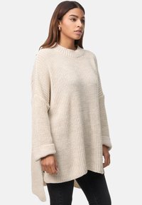 Chunky Strickpullover in hellem Beige mit hohem Kragen, oversized Passform und umgeschlagenen Bündchen, der ein strukturiertes gewebtes Muster aufweist.