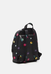Černý kožený batoh s barevnými malými květinovými vzory, dvojitými popruhy, rukojetí na vrchu a zadní kapsou na zip na bílém pozadí.