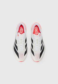 Black and white athletic shoes with a mesh upper and three striped accents. Neon red details on the interior and logo are visible.