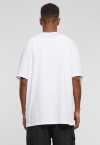 Hvit oversized T-skjorte med kort erme, laget av bomull, med rett kant og uten synlige mønstre eller detaljer.
