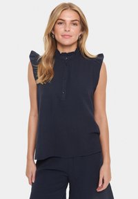 Kara jūras zila bez piedurknēm augšdaļa ar teksturētu apdari, ar volānu plecu detaļām, pogām priekšā un brīvu piegriezumu.