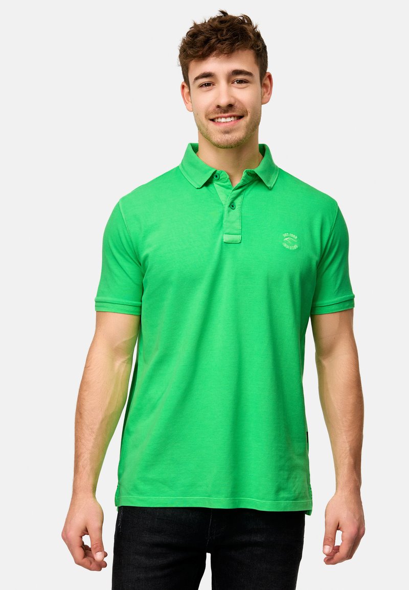 Grønn polo-skjorte laget av myk bomull, med klassisk krage, to-knapp knappestolpe, korte ermer og en liten logo på brystet.