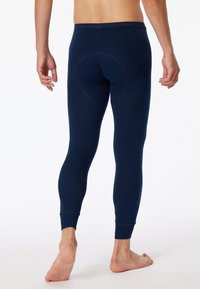 Leggings thermiques bleu marine en tissu doux, avec un design ajusté, des bretelles aux chevilles et un détail de couture circulaire à l'arrière.