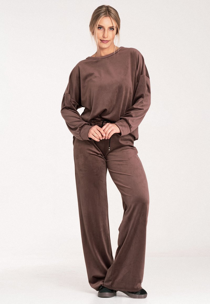 Brązowy zestaw wypoczynkowy z aksamitu, składający się z długiego rękawa w luźnym kroju oraz spodni z szerokimi nogawkami, oba o miękkiej strukturze i elastycznej talii.