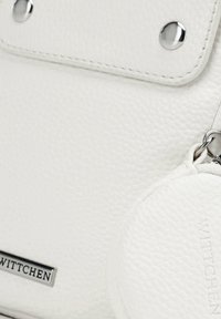 Weißes strukturiertes Lederhandtasche mit Klappenverschluss, silbernem Zubehör und einem kleinen runden Tag mit dem Markennamen "Wittchen".