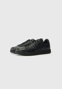 Sneakers din piele neagră, cu un material superior texturat, vârf rotund, talpă plată și detalii cu logo pe lateral și pe limbă. Design cu șireturi.