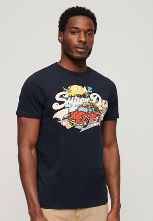 Camiseta de algodón de color azul marino con un diseño gráfico colorido de un coche y palmeras. Mangas cortas y escote redondo con textura mínima.