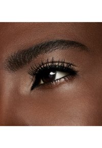 Close-up van een donkerbruine oog met lange wimpers, een gedefinieerde wenkbrauw en een gladde huidstructuur. De iris is diep bruin met een glanzende glans.