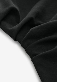 Tissu en coton noir avec une texture lisse, présentant des plis doux et des rides subtiles, mettant en avant sa drape flexible et sa polyvalence.