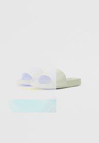 Hvite gummislidesandaler med en glatt overflate, åpen tå-design og en såle som føles som en pute. Har minimal merkevare på den øvre stroppen.