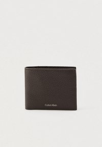 Cartera de piel marrón con acabado texturizado, diseño de doble pliegue y sutil logotipo de "Calvin Klein" en la parte inferior delantera. Compacta y funcional.