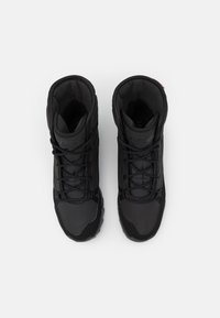 Botas de senderismo negras que combinan materiales lisos y texturizados, con un diseño de tobillo alto y suela de goma duradera para una mejor tracción.