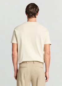 T-shirt crème à manches courtes avec une texture lisse, col rond et coupe décontractée, assorti à un pantalon beige clair.